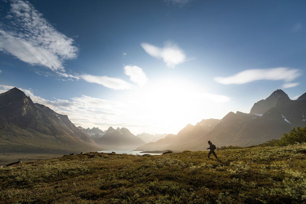 Un randonneur dans le fjord Tasermiut entouré de montagnes