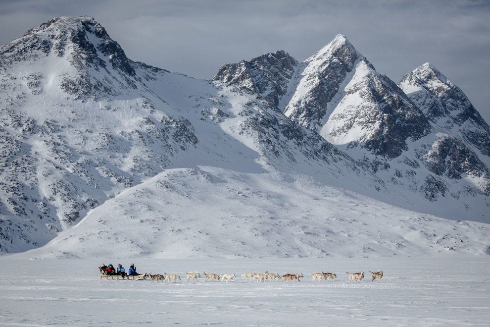 Traîneau à chiens sous des pics éloignés dans la partie de Tasiilaq de l'Est du Groenland