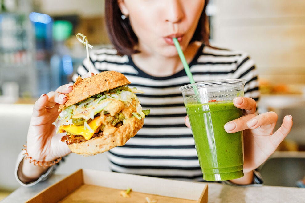 Femme appréciant un hamburger et un smoothie végétaliens