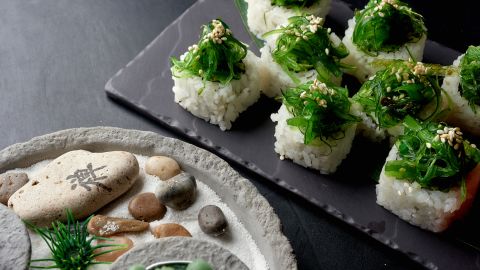 Les rouleaux de sushi sont enveloppés dans des feuilles de papier appelées nori.  Ici, le wakame garnit le dessus des rouleaux de sushi.